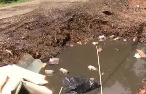 Vecindario de Alabama bajo riesgo sanitario por gran bache Gran bache profundo en un callejón urbano pavimentado con acumulación de escombros y daños en la acera.