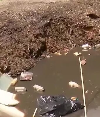 Vecindario de Alabama bajo riesgo sanitario por gran bache Gran bache profundo en un callejón urbano pavimentado con acumulación de escombros y daños en la acera.