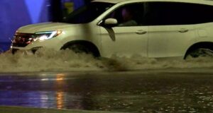 Sequía en Alabama disminuye tras intensas lluvias recientes Camioneta blanca atravesando una calle completamente inundada durante una tormenta.