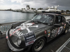 Rallye de la Cerámica se suspende tras trágico accidente Un coche clásico Porsche de rally gris con el logo de St. Pauli estacionado en un muelle náutico junto a yates.