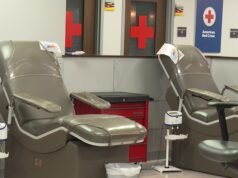 Donación de sangre en Alabama bajo alerta por escasez Sillones vacíos de color gris en una sala de donación de la Cruz Roja Americana con logotipos de cruces rojas al fondo.