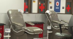 Donación de sangre en Alabama bajo alerta por escasez Sillones vacíos de color gris en una sala de donación de la Cruz Roja Americana con logotipos de cruces rojas al fondo.
