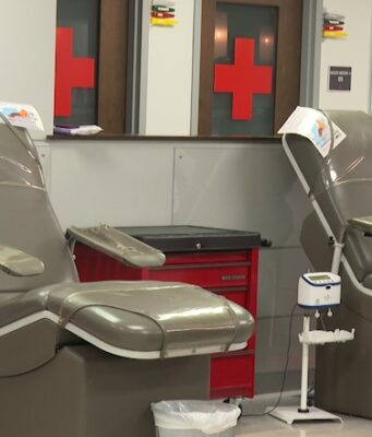 Donación de sangre en Alabama bajo alerta por escasez Sillones vacíos de color gris en una sala de donación de la Cruz Roja Americana con logotipos de cruces rojas al fondo.
