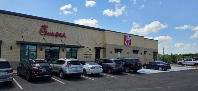 Fachada exterior de un restaurante Chick-fil-A en Alabama con vehículos estacionados frente al establecimiento en un día despejado.