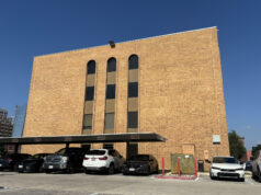 Cortes de inmigración aplican polémicas audiencias masivas Edificio de ladrillo marrón de la corte de inmigración en San Antonio con estacionamiento frontal de automóviles.
