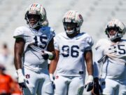 Arresto en Alabama: Da’Shawn Womack enfrenta cargos penales Tres jugadores de fútbol americano de Auburn con uniforme blanco y cascos protectores durante una práctica en Alabama.