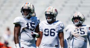 Arresto en Alabama: Da’Shawn Womack enfrenta cargos penales Tres jugadores de fútbol americano de Auburn con uniforme blanco y cascos protectores durante una práctica en Alabama.