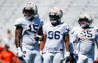 Arresto en Alabama: Da’Shawn Womack enfrenta cargos penales Tres jugadores de fútbol americano de Auburn con uniforme blanco y cascos protectores durante una práctica en Alabama.