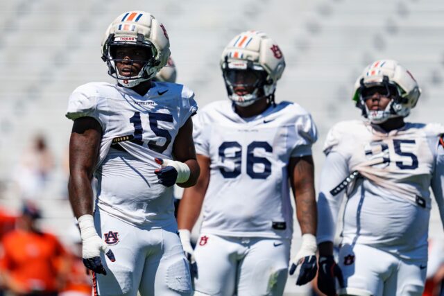 dashawn-womack-auburn-alabama-arresto-jugador Tres jugadores de fútbol americano de Auburn con uniforme blanco y cascos protectores durante una práctica en Alabama.