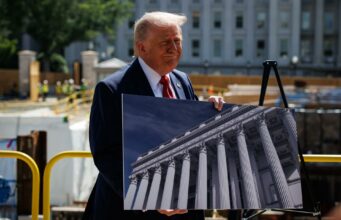 Donald Trump respalda a Abelardo de la Espriella en Colombia Donald Trump sonríe sosteniendo una fotografía de un edificio con columnas clásicas durante un evento de prensa exterior.