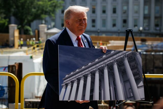 Donald Trump respalda a Abelardo de la Espriella en Colombia Donald Trump sonríe sosteniendo una fotografía de un edificio con columnas clásicas durante un evento de prensa exterior.