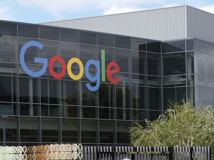 Inteligencia artificial impulsa a Alphabet a vender acciones por $80.000 millones Fachada acristalada de un edificio de Google que refleja el cielo en su sede corporativa de Alphabet.