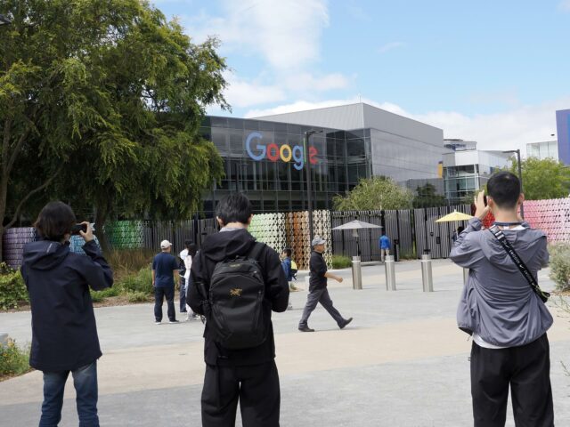 Turistas fotografían las instalaciones de la sede principal de Google con el logotipo corporativo al fondo.
