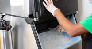 Inspección de alimentos en Birmingham provoca cierres temporales Un empleado con guantes de protección extrae hielo con una pala desde una máquina expendedora de acero inoxidable.