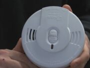 Detectores de humo gratis en Moody: cómo solicitarlos Manos de un bombero sosteniendo un detector de humo circular blanco de la marca Kidde para instalación gratuita en Moody.