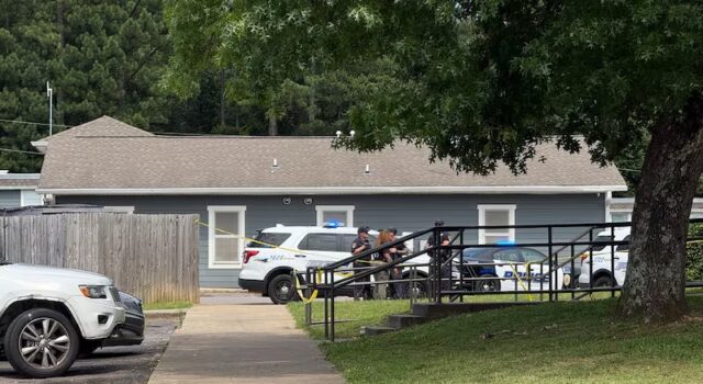 Investigan homicidio en Birmingham tras una discusión armada Patrullas policiales y cinta de seguridad amarilla frente a una vivienda gris durante investigación en Birmingham.