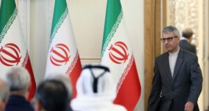 Acuerdo con EE.UU.: Irán frena la expectativa de Donald Trump Funcionario iraní camina en una sala de reuniones con banderas oficiales de Irán al fondo.