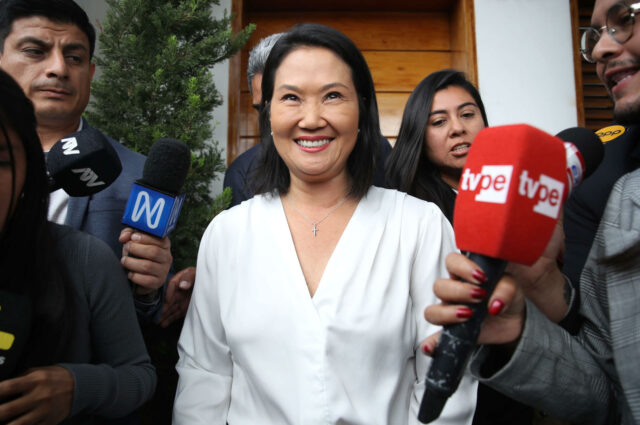 La candidata presidencial Keiko Fujimori sonríe rodeada de micrófonos y periodistas durante la jornada electoral en Lima.