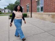 Maestra de DLI regresa a Escuelas de Birmingham Maestra de DLI Reiniela Ortiz camina frente al edificio de ladrillo rojo de una escuela en Alabama.