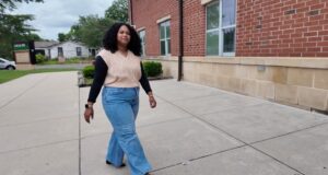 Maestra de DLI regresa a Escuelas de Birmingham Maestra de DLI Reiniela Ortiz camina frente al edificio de ladrillo rojo de una escuela en Alabama.