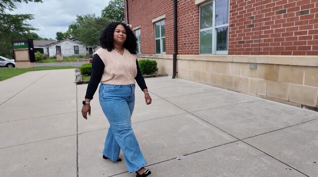 Maestra de DLI regresa a Escuelas de Birmingham Maestra de DLI Reiniela Ortiz camina frente al edificio de ladrillo rojo de una escuela en Alabama.