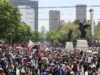 Maestros en México inician huelga y cercan el Zócalo Multitud de maestros en México marchando por una avenida con banderas en protesta contra el gobierno.
