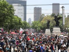 Maestros en México inician huelga y cercan el Zócalo Multitud de maestros en México marchando por una avenida con banderas en protesta contra el gobierno.