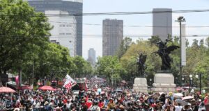 Maestros en México inician huelga y cercan el Zócalo Multitud de maestros en México marchando por una avenida con banderas en protesta contra el gobierno.