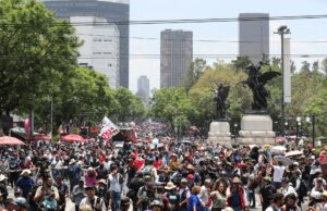 Maestros en México inician huelga y cercan el Zócalo Multitud de maestros en México marchando por una avenida con banderas en protesta contra el gobierno.