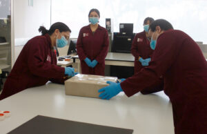México recupera valioso documento histórico de Hernán Cortés Personal calificado de México con batas guindas y guantes azules inspecciona una caja con un documento histórico.