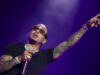 Gira de Ozuna 2026 arranca con espectacular concierto en Ibiza El cantante de reggaetón Ozuna cantando con micrófono y señalando hacia arriba con gafas de sol oscuras en concierto.