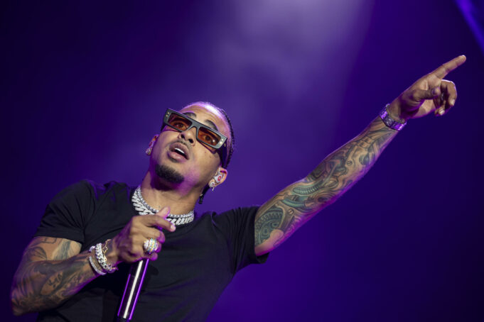 Gira de Ozuna 2026 arranca con espectacular concierto en Ibiza El cantante de reggaetón Ozuna cantando con micrófono y señalando hacia arriba con gafas de sol oscuras en concierto.