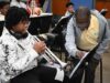 Programa de verano en Alabama impulsa arte y música Estudiante tocando la trompeta junto a un instructor de música que señala una partitura en el campamento June Tunes.