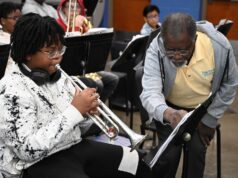 Programa de verano en Alabama impulsa arte y música Estudiante tocando la trompeta junto a un instructor de música que señala una partitura en el campamento June Tunes.