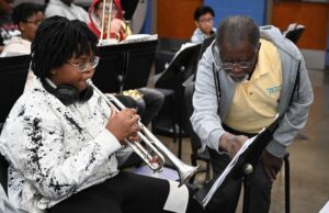 Programa de verano en Alabama impulsa arte y música Estudiante tocando la trompeta junto a un instructor de música que señala una partitura en el campamento June Tunes.