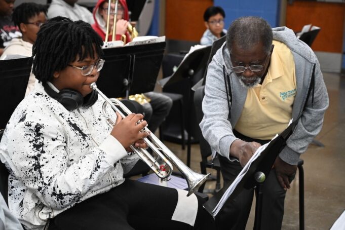 Programa de verano en Alabama impulsa arte y música Estudiante tocando la trompeta junto a un instructor de música que señala una partitura en el campamento June Tunes.