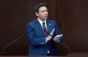 Reducción de impuestos inmobiliarios en Florida irá a voto El gobernador de Florida Ron DeSantis con traje azul en un podio hablando sobre la reducción de impuestos inmobiliarios.