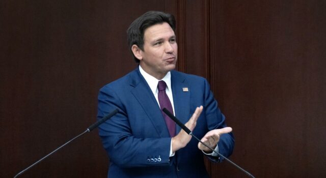 Reducción de impuestos inmobiliarios en Florida irá a voto El gobernador de Florida Ron DeSantis con traje azul en un podio hablando sobre la reducción de impuestos inmobiliarios.