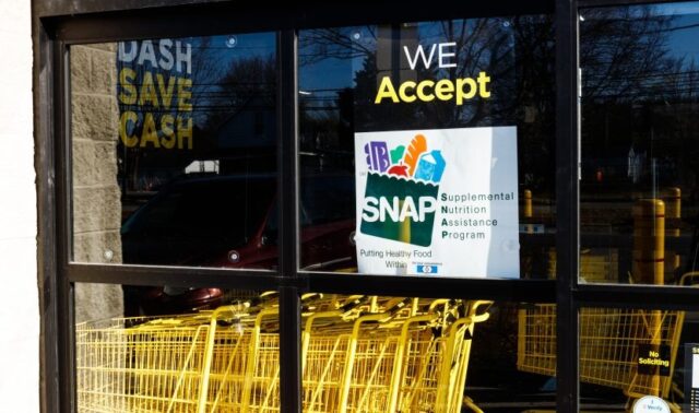 Letrero oficial del programa SNAP en la ventana de un supermercado con carritos de compra amarillos en Alabama.