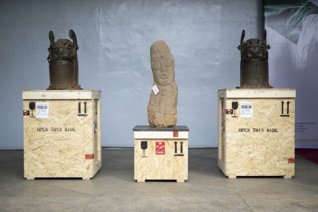 Tres valiosos artefactos coloniales del Reino de Benín colocados sobre cajas de transporte de madera listas para su devolución.
