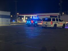 Tiroteo en Midfield activa investigación policial urgente Patrullas de policía con luces intermitentes azules encendidas estacionadas de noche en el estacionamiento de una gasolinera en Midfield durante una investigación.
