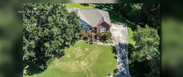 Vista aérea de una casa en Trussville con un águila gigante y el texto USA 250 dibujados en el césped.