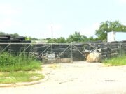 Anniston exige limpiar vertedero ilegal de neumáticos Cerca metálica rodeada de vegetación que protege un vertedero con miles de neumáticos apilados en Anniston.
