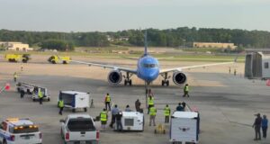 Breeze Airways estrena nuevos vuelos directos desde Birmingham Avión azul de Breeze Airways en la pista del aeropuerto de Birmingham atendido por personal terrestre.