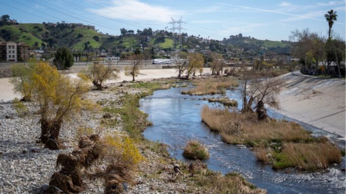Contaminación por PFAS afecta el 98% de ríos en la Nación Canal de río contaminado por PFAS rodeado de vegetación, infraestructura eléctrica y viviendas urbanas.