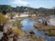 Contaminación por PFAS afecta el 98% de ríos en la Nación Canal de río contaminado por PFAS rodeado de vegetación, infraestructura eléctrica y viviendas urbanas.