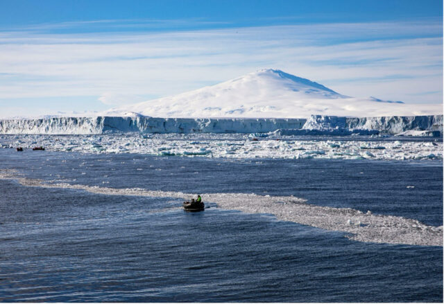Paisaje polar con glaciares derretidos y embarcaciones navegando en el océano helado de la Antártida.