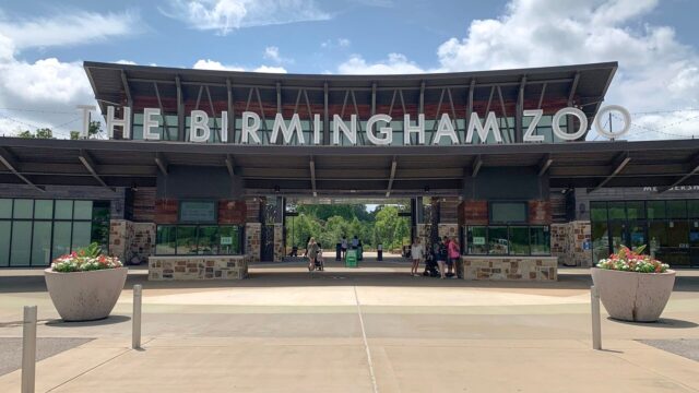 Entrada principal del Zoológico de Birmingham en Alabama con el letrero gigante en letras blancas bajo un cielo despejado.