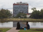 Examen UNAM 2026 bajo revisión por sospecha de uso de IA Estudiantes sentados frente al espejo de agua con el edificio de Rectoría de la UNAM al fondo en México.