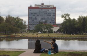 Examen UNAM 2026 bajo revisión por sospecha de uso de IA Estudiantes sentados frente al espejo de agua con el edificio de Rectoría de la UNAM al fondo en México.